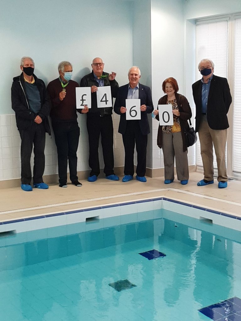 Great Missenden Rotary Club Members standing by the pool holding a £460 sign