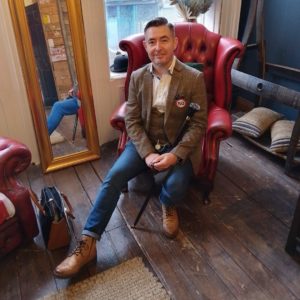 Man smartly dressed in tweed jacket sitting in comfortable lounge chair