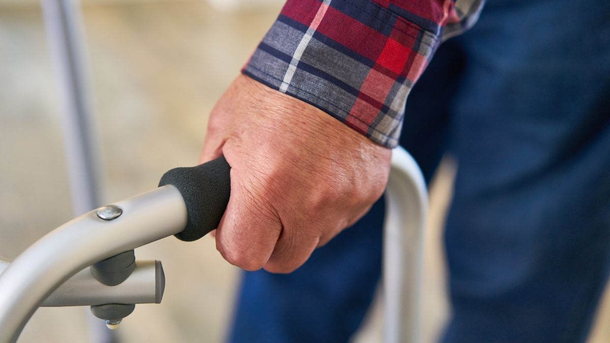 Close up of a man walking with a rollator walking frame.