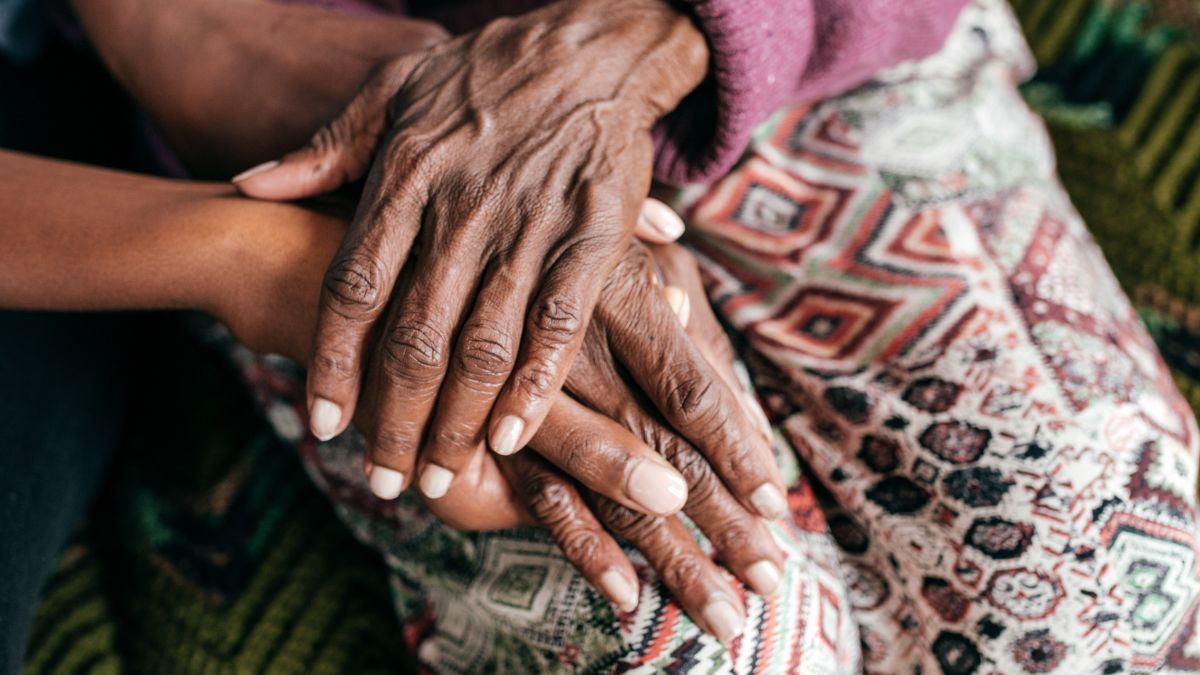 Elderly person's hand, holding the hand of someone younger