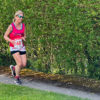 Smiling woman taking part in a running race. She is wearing a bright pink running vest with the branding for the Chiltern Neuro Centre. Her race bib is showing number 60.