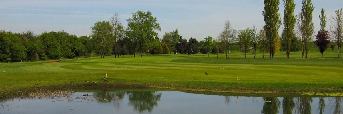 View looking over a after feature towards the green of a golf course.